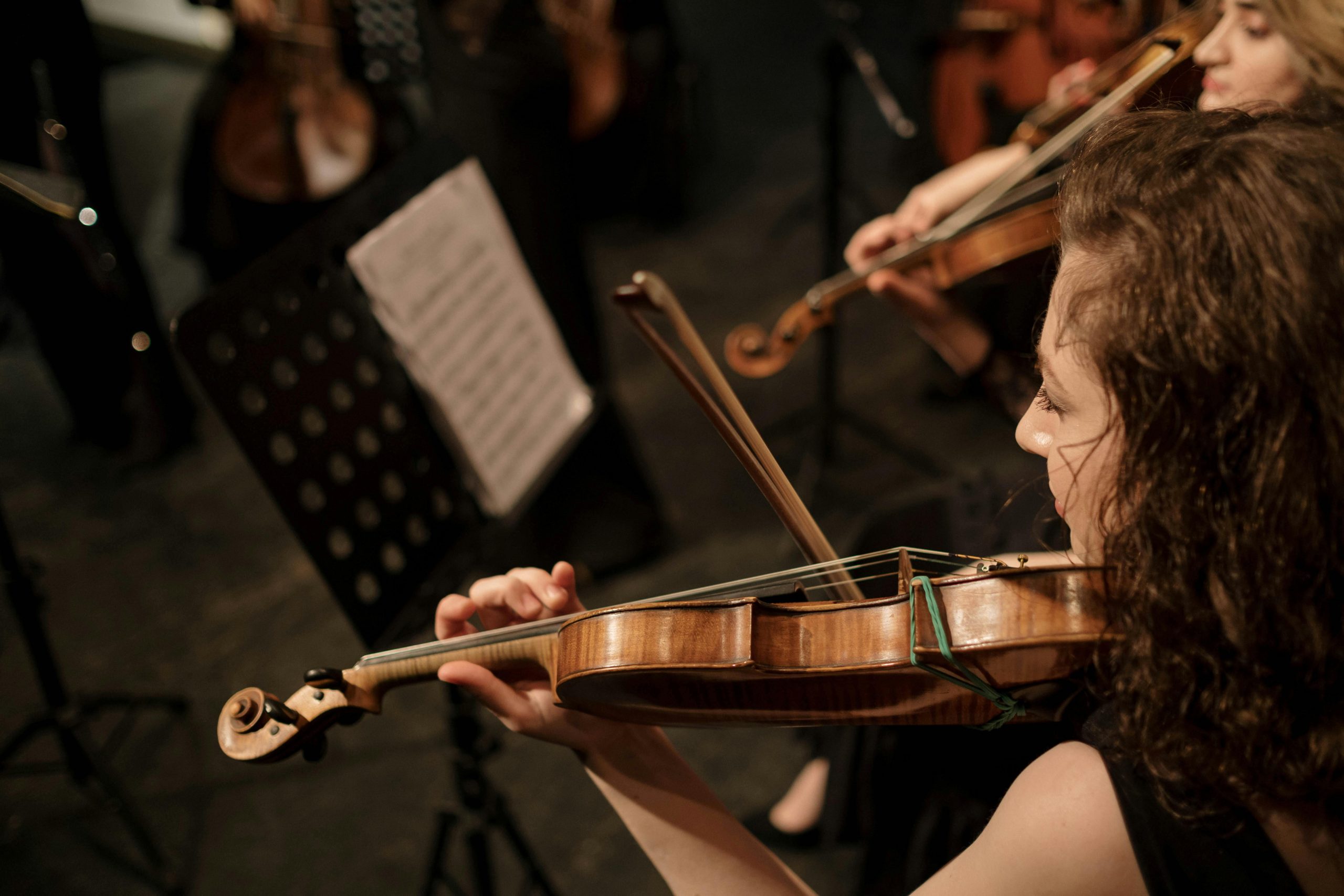 A skilled female violinist in an orchestra playing with elegance and passion.