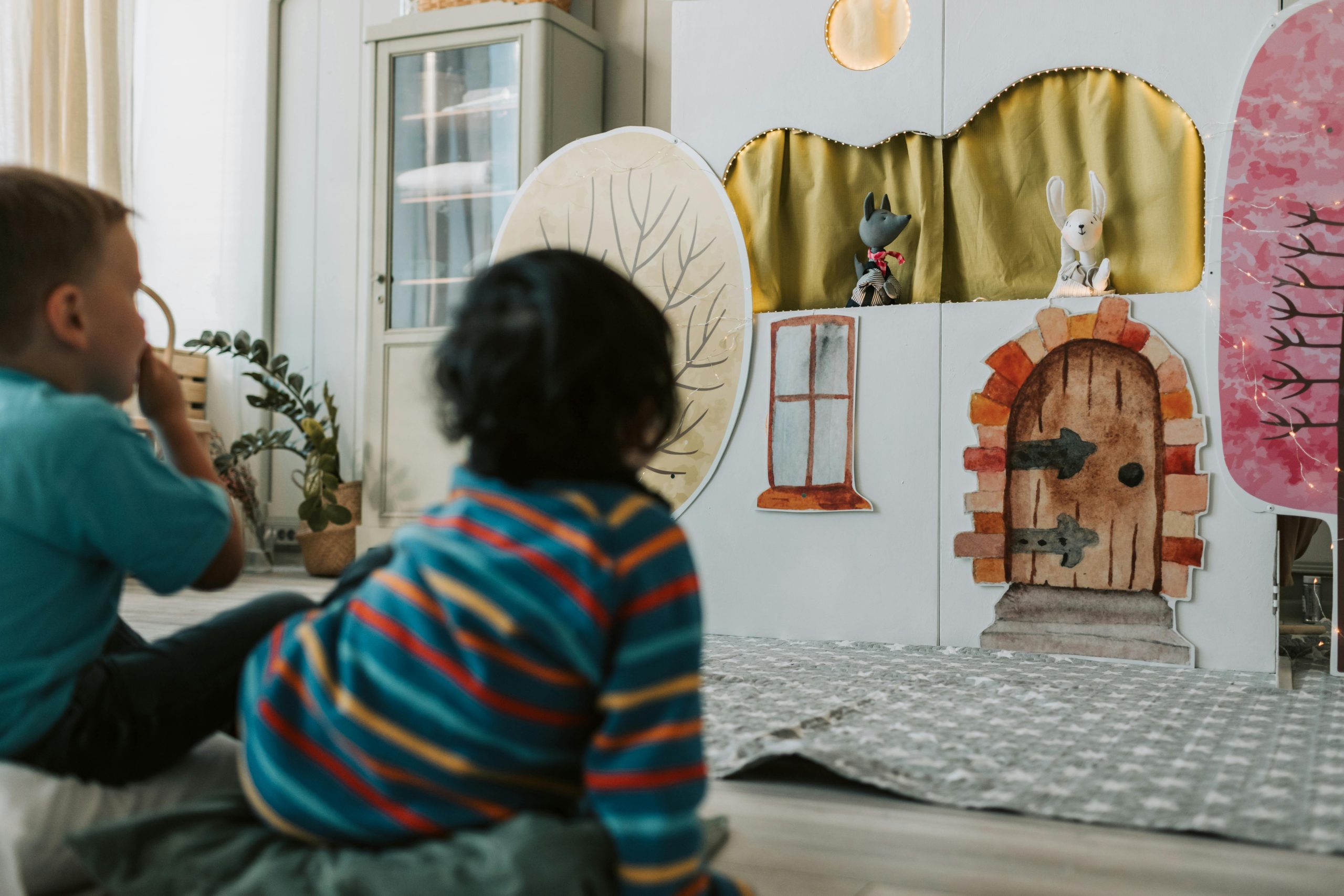 Kids engaged in a puppet theater, watching with fascination indoors.